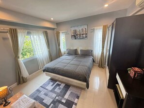 A modern bedroom with a bed, curtains, a painting, and a black TV stand. - Villa 9 - Spacious 2 Bedroom Villa with Pool Near Beaches, Dining and Nightlife near Fisherman's Village (Ko Samui District)