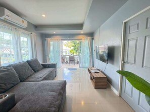 A modern living room with a sofa, a TV, and a sliding glass door leading to an outdoor area. - Villa 9 - Spacious 2 Bedroom Villa with Pool Near Beaches, Dining and Nightlife near Fisherman's Village (Ko Samui District)