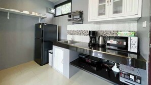 Una cucina compatta con frigorifero, microonde, macchina del caffè e un piccolo lavandino.