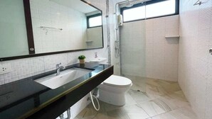 Un bagno moderno con un ampio specchio, un lavandino, un water e una zona doccia.