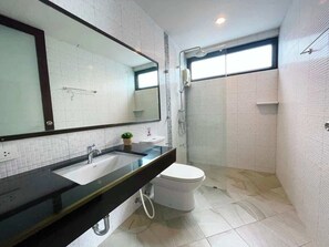 Ein modernes Badezimmer mit großem Spiegel, Waschbecken, Toilette und Duschbereich.