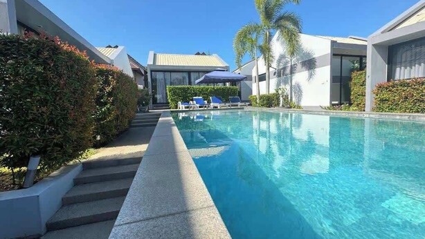 Un hotel moderno con piscina, lettini e palme.