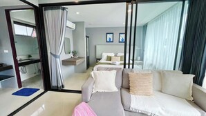 Una habitación de hotel moderna con sofá, cama, baño y zona de comedor.