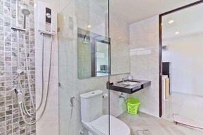 Ein modernes Badezimmer mit Duschkabine aus Glas, Toilette, Waschbecken und Spiegel.