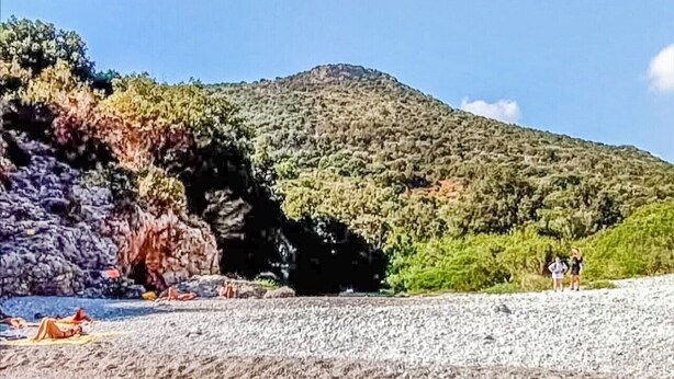 A beach with clear water, rocky shore, and a hill with vegetation. - Sea and Sun House - Sun Option (Vibonati)