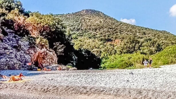 A beach with clear water, rocky shore, and a hill with vegetation. - Sea and Sun House - Sea Option (Vibonati)