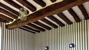Een slaapkamer met een bed, een houten vloer, een gestreepte wand en een hangende lamp.