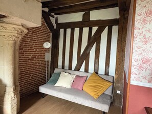 Ein gemütliches Zimmer mit freiliegenden Holzbalken, einer Backsteinwand und einer gepolsterten Bank mit Kissen.