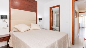 Quarto com cama, mesas de cabeceira, cabeceira de madeira e espelho.