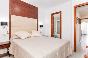 A bedroom with a bed, bedside tables, a wooden headboard, and a mirror. - 284 La Santa by Mallorca Charme (Ca´n Picafort)