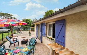 Eine Terrasse mit Gartenmöbeln, einem bunten Sonnenschirm und einem Fahrrad.