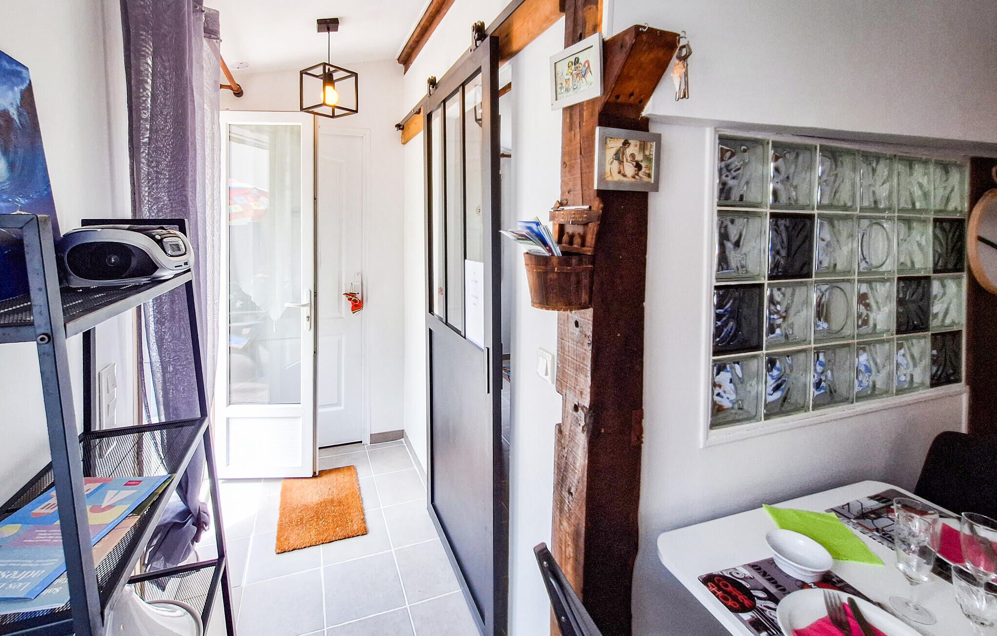 A narrow hallway with a door leading to a room, a staircase, and a dining area with a table set for two.