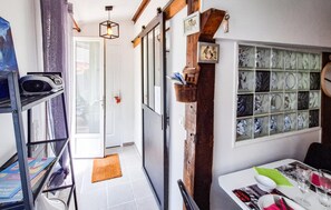 Ein schmaler Flur mit einer Tür zu einem Zimmer, einer Treppe und einem Essbereich mit Tisch für zwei Personen.