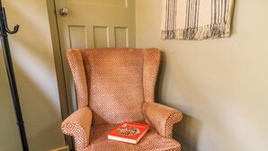 Un fauteuil à motifs, un livre, une lampe de sol noire et une porte avec un interrupteur.