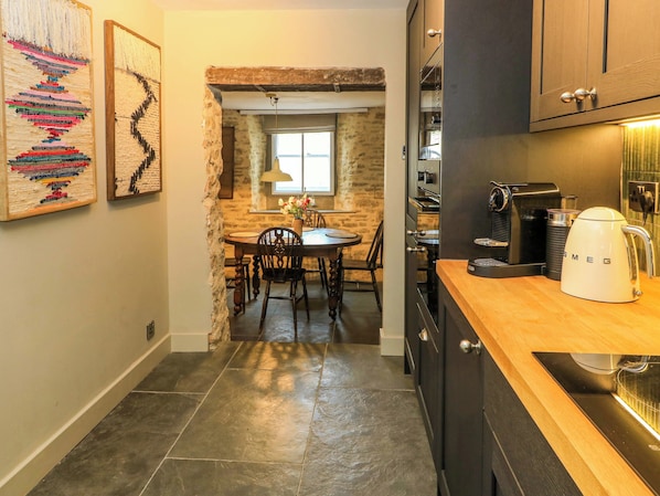 Eine Küche mit dunklen Schränken, einer Kaffeemaschine und einem gefliesten Boden.