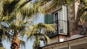 Un edificio con balcón, palmeras y cielo despejado.