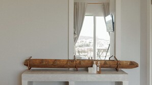 Una habitación con un espejo grande, un banco de madera y un televisor en la pared.