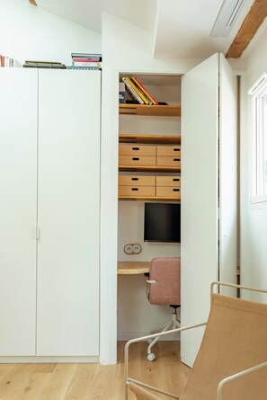 Ein Arbeitsraum mit Schreibtisch, Stuhl und Bücherregal mit Büchern und einem Fernseher.