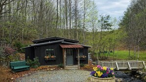 Ein rustikales Blockhaus mit einem Schotterweg, einer hölzernen Bank und einem Blumentopf.