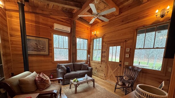 Ein gemütliches Blockhaus-Interieur mit Sofa, Sessel, Couchtisch und einem dekorativen Bärenstuhl.
