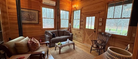 A cozy cabin interior with a sofa, armchair, coffee table, and a decorative bear chair.