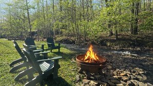 Ein Lagerfeuer mit Stühlen und einem steinigen Flussufer.