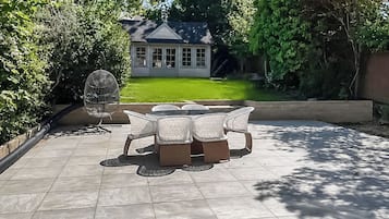 A patio with a table and chairs, a birdcage, and a house in the background.