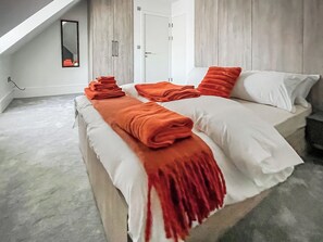 Een moderne slaapkamer met een bed, witte lakens en oranje accenten.