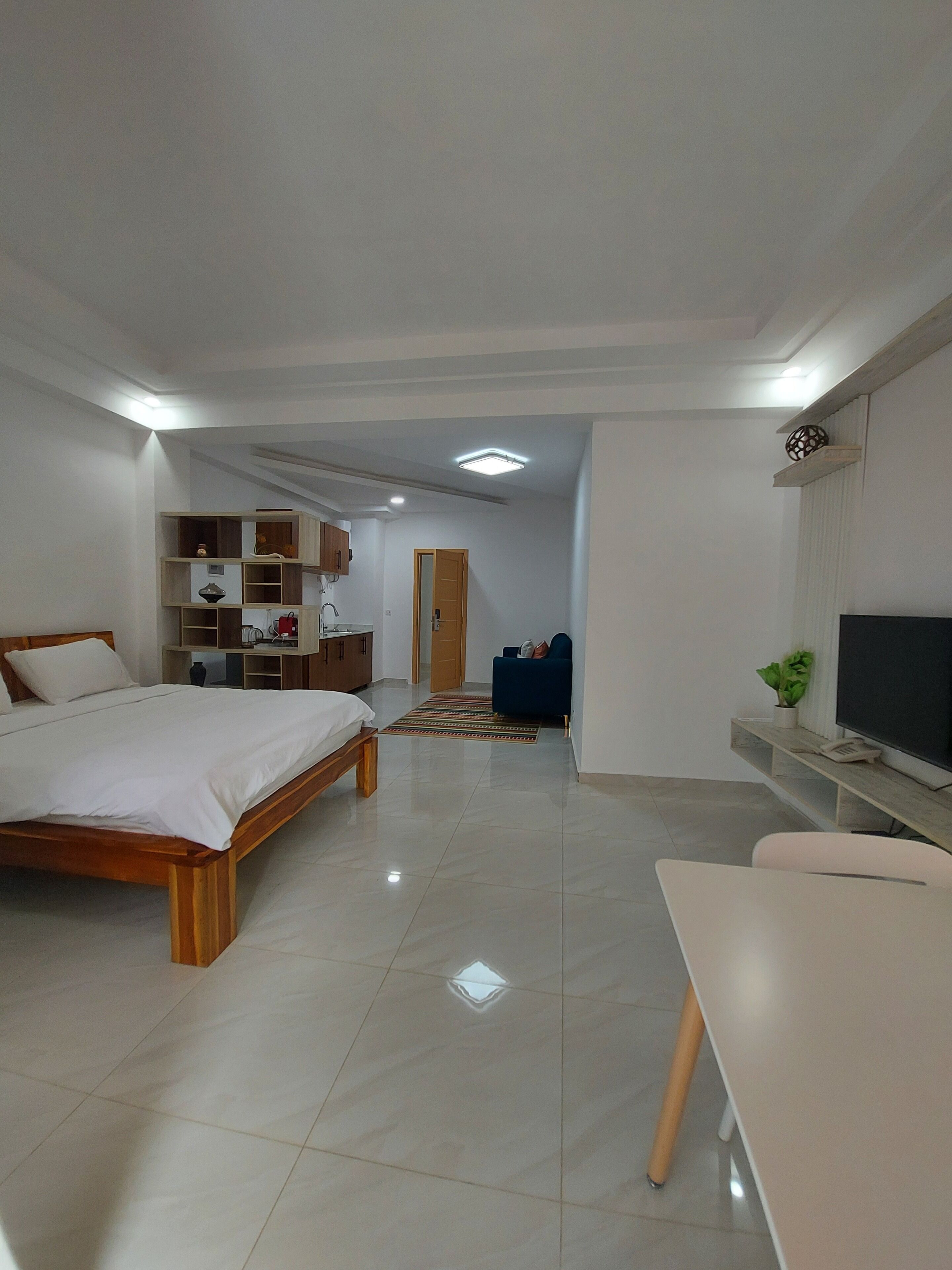 Une chambre d’hôtel moderne équipée d’un lit, d’un bureau, d’une télévision et d’une kitchenette.