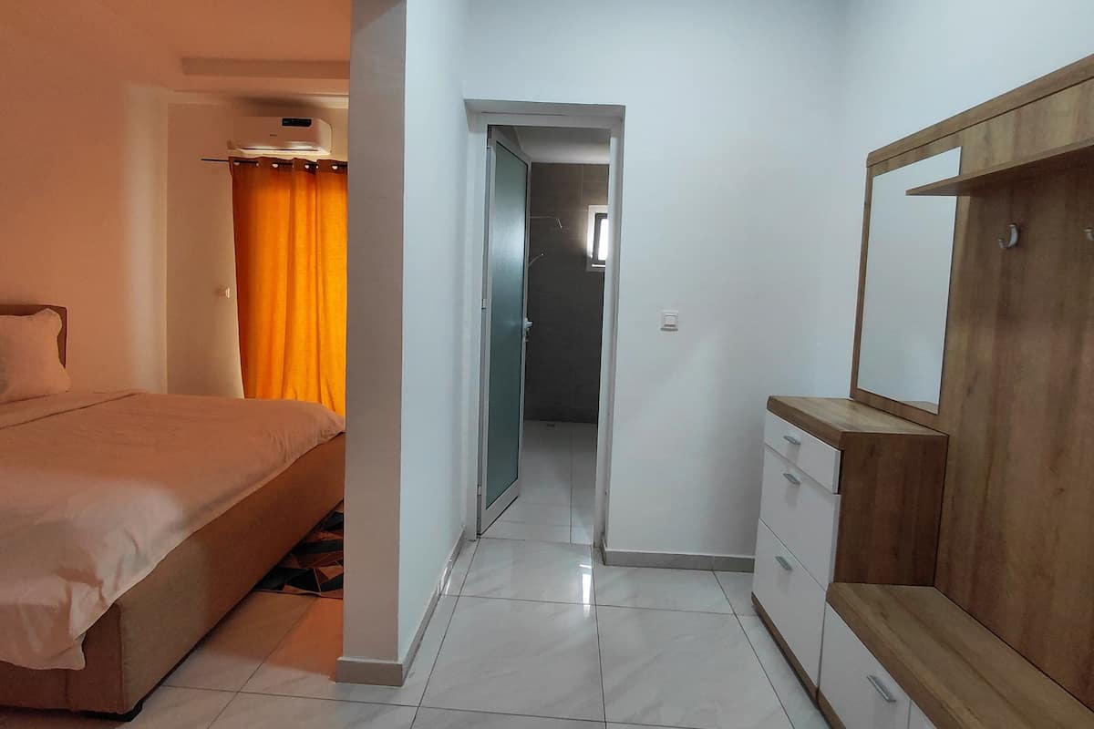 A hotel room with a bed, a wardrobe, a mirror, and a bathroom visible through an open door.