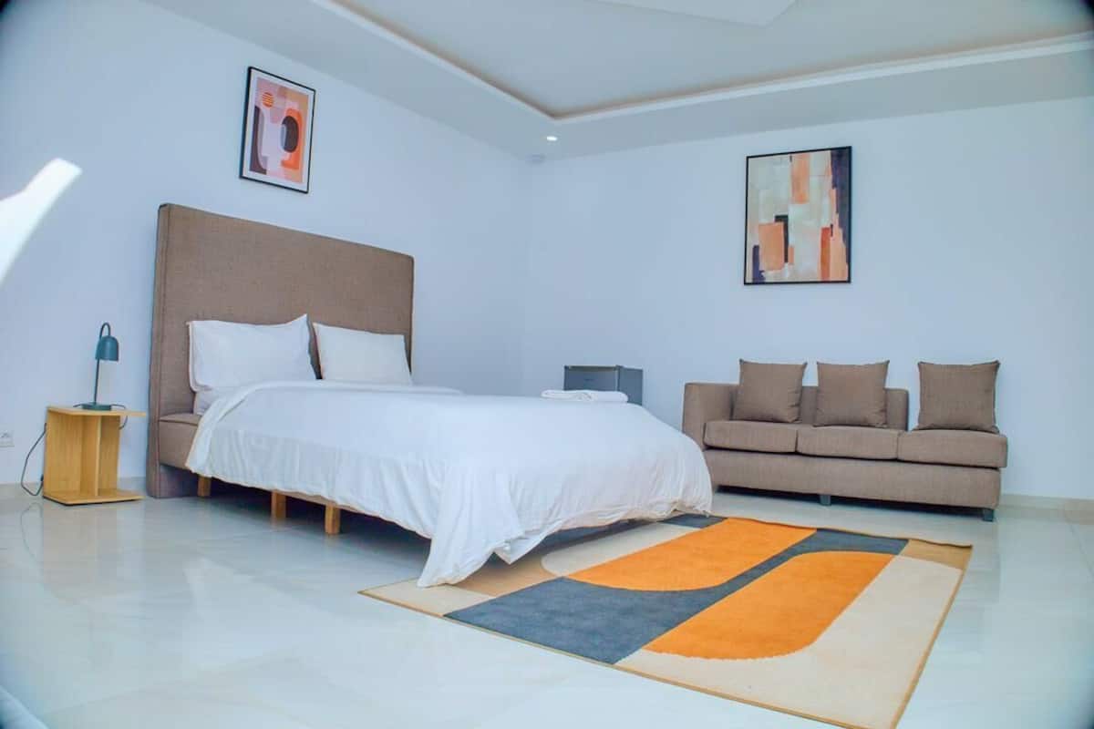 A modern bedroom with a bed, a sofa, a bedside table, and a rug.