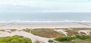 Een strand met een zandstrand, enkele kleine gebouwen en begroeiing op de voorgrond.