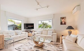 Een moderne woonkamer met twee banken, een glazen salontafel en een flatscreen televisie.