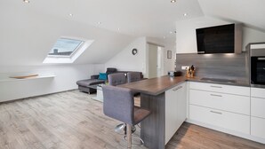 A modern kitchen with a bar area, a dining space with a high ceiling, and a skylight. - Apartment 'Conny' with Mountain View, Balcony and Wi-Fi (Bühl)