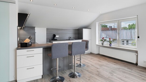 A modern kitchen with two bar stools, a built-in oven, and a window with a view of the outside. - Apartment 'Conny' with Mountain View, Balcony and Wi-Fi (Bühl)