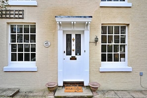 A white door with a glass panel, a welcome mat, and a number plaque. - Finest Retreats | Yew Cottage (Tunbridge Wells)