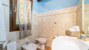 Une salle de bain équipée d’un lavabo, d’un bidet, de toilettes et d’une baignoire.