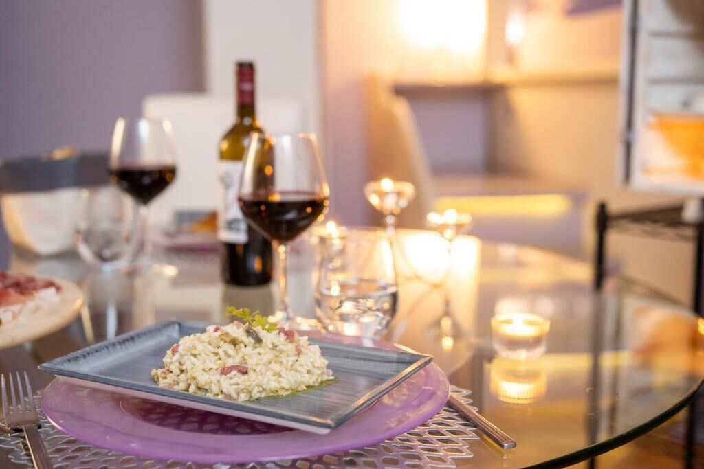 Une table à manger avec une assiette de nourriture, des verres à vin et une bouteille de vin.
