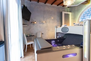 Habitación pequeña con una cama individual superior e inferior, una mesita, una silla y un televisor montado en la pared.