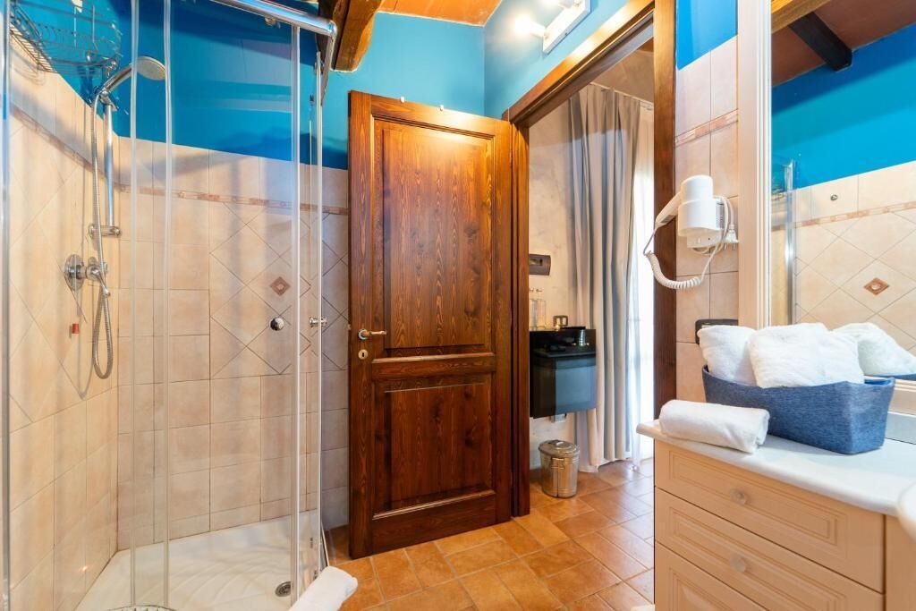 Ein Badezimmer mit Dusche, einer Holztür, einem Handtuchhalter und einem Waschbecken mit Spiegel.