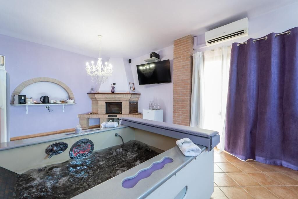 Una habitación con una bañera de hidromasaje de piedra, una chimenea, un televisor montado en la pared y una zona de ducha.