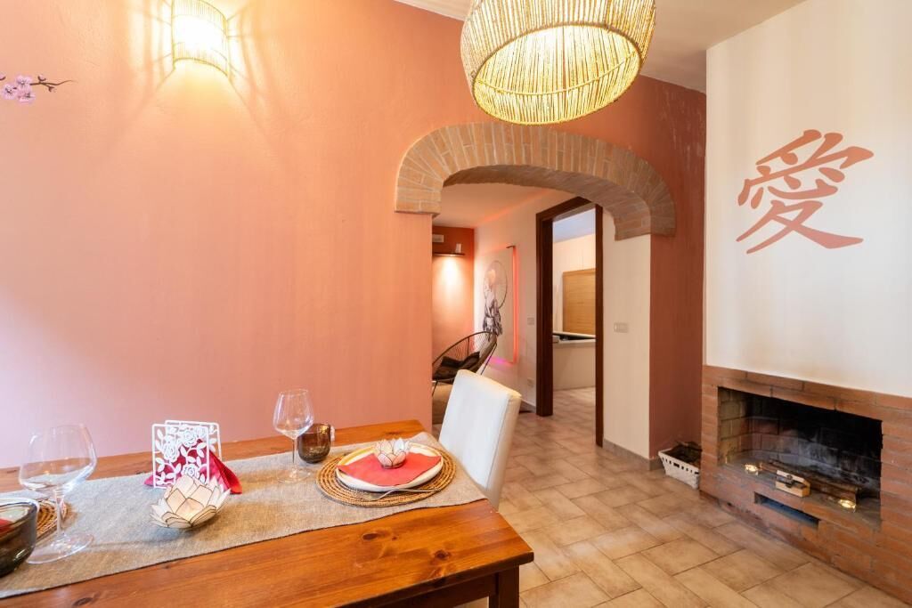 Un comedor con mesa de madera, sillas, chimenea y una pared con un gran caracter chino.