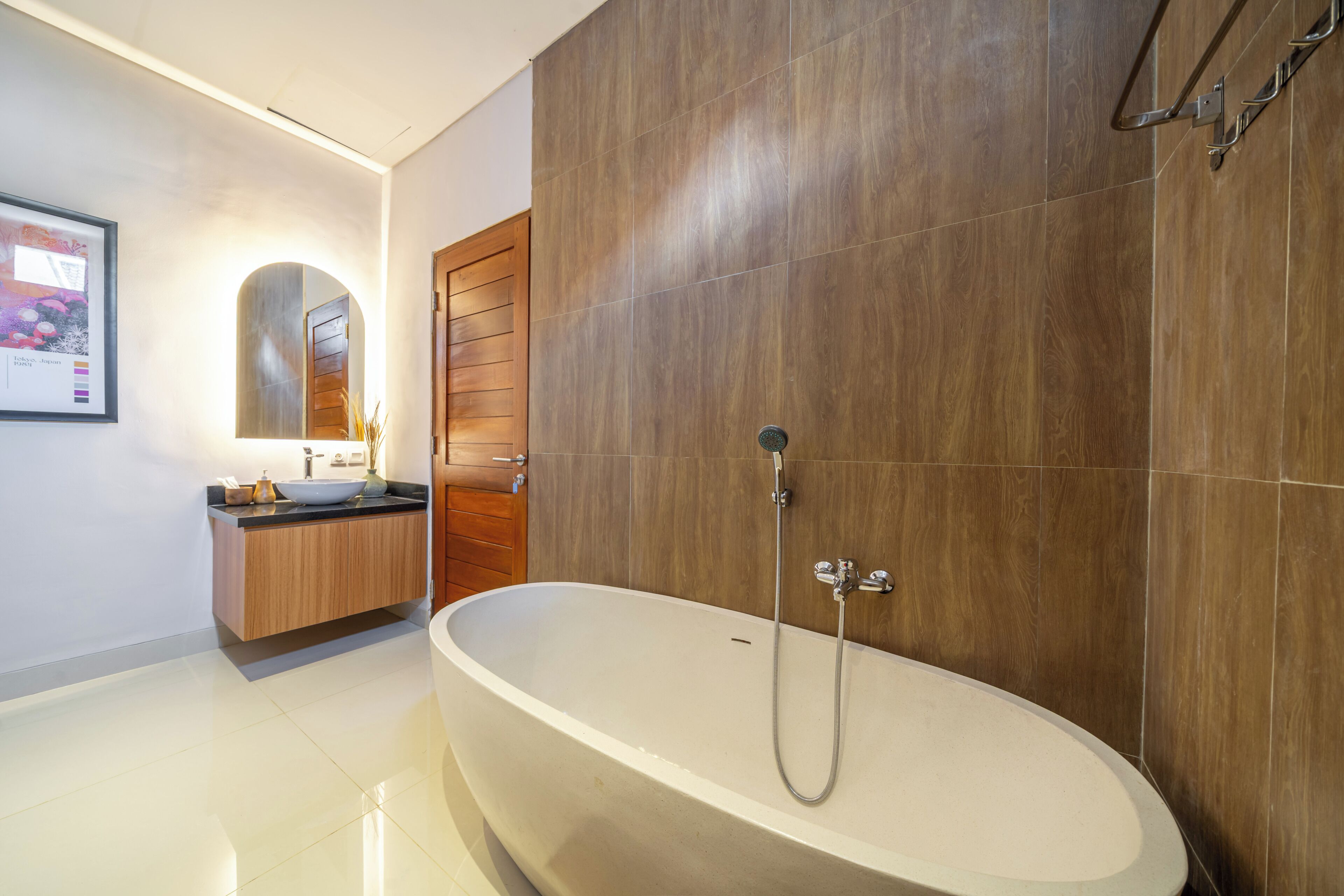 A modern bathroom with a freestanding bathtub, a wooden vanity, and a large mirror.