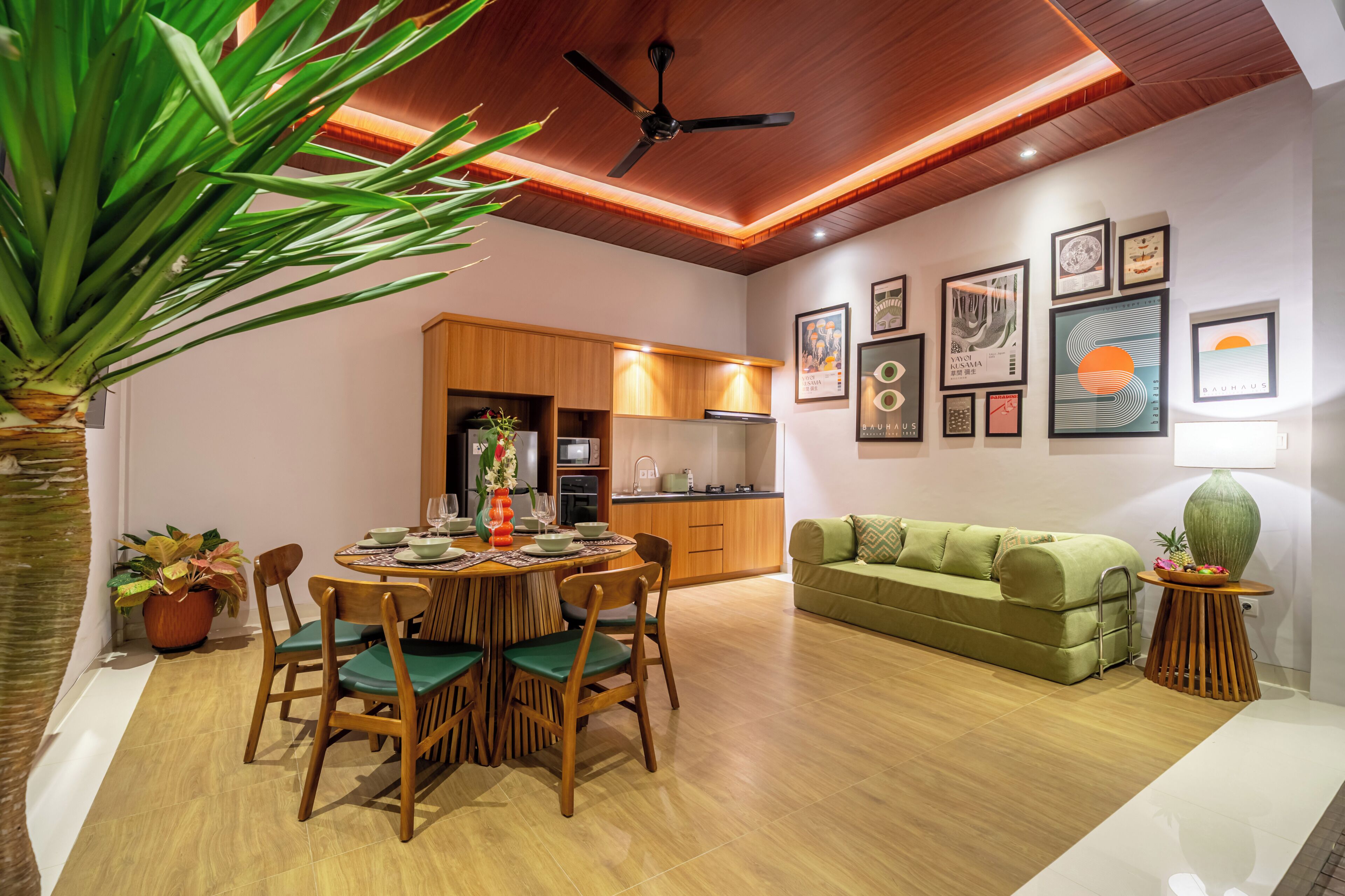 A modern living room with a dining area, wooden ceiling, and artwork on the walls.