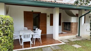 A covered patio with a table and chairs, a brick fireplace, and a small garden area. - Lovely Villa With Pool, Garden and Fireplace (San Michele al Tagliamento)