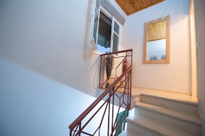 Eine Treppe mit Holzgeländer und Blick zum Himmel durch ein offenes Fenster.