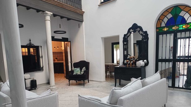 A spacious living area with a white sofa, a black armchair, and a large mirror.