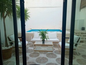 Ein Poolbereich mit weißen Liegestühlen, einem Glastisch und einem Blumentopf.