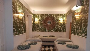 A small, cozy room with two beds, a checkered floor, and tropical wallpaper.
