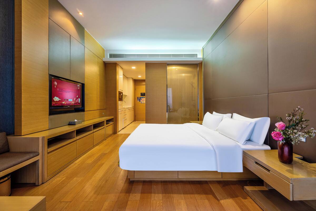 Una habitación de hotel moderna con cama, televisor, escritorio y baño.
